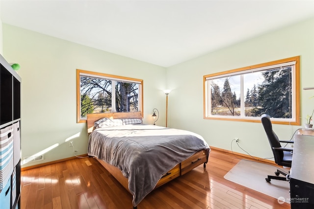 bedroom with multiple windows and hardwood / wood-style floors