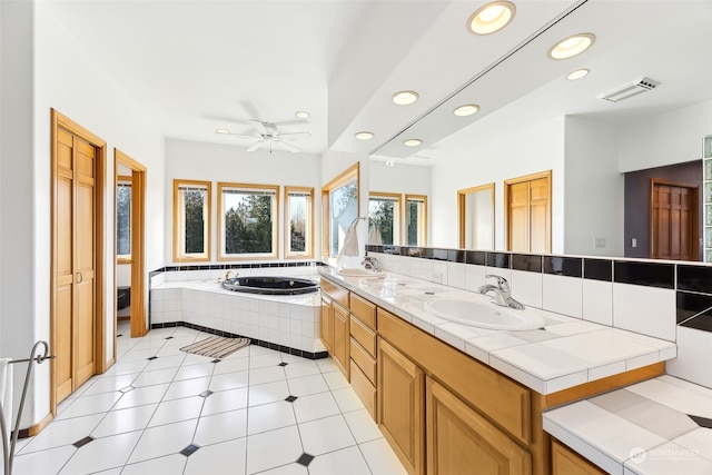 bathroom featuring toilet, vanity, ceiling fan, tiled bath, and tile patterned flooring