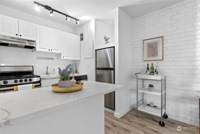 kitchen with sink, light stone counters, white cabinetry, light hardwood / wood-style flooring, and stainless steel appliances