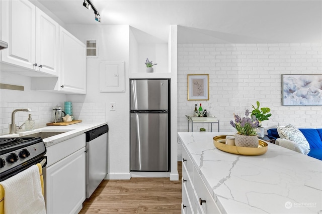 kitchen featuring sink, light stone counters, light wood-type flooring, appliances with stainless steel finishes, and white cabinets