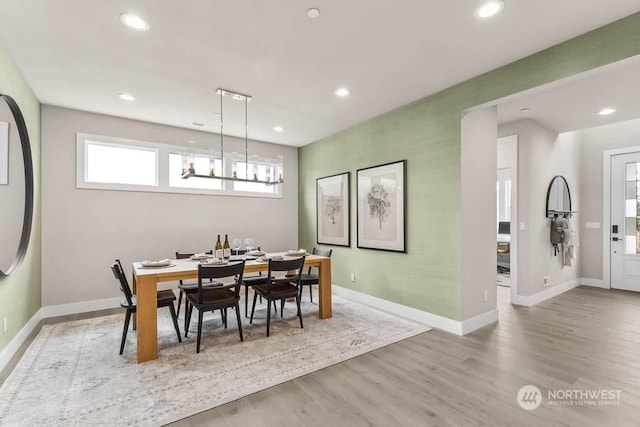 dining space with light hardwood / wood-style floors and a chandelier