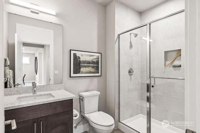 bathroom featuring toilet, vanity, and a shower with shower door