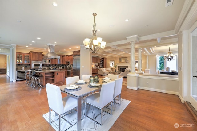 dining room with decorative columns, ornamental molding, and a notable chandelier