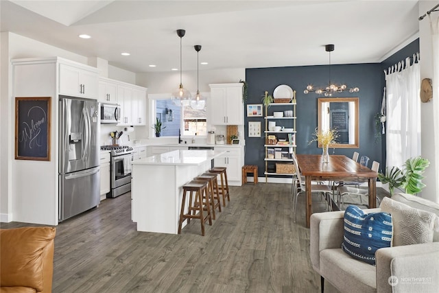 kitchen with decorative light fixtures, stainless steel appliances, a center island, and white cabinets