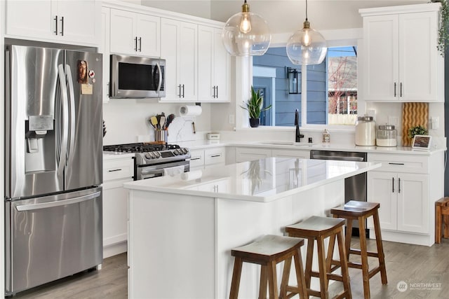 kitchen with stainless steel appliances, a center island, white cabinets, and decorative light fixtures