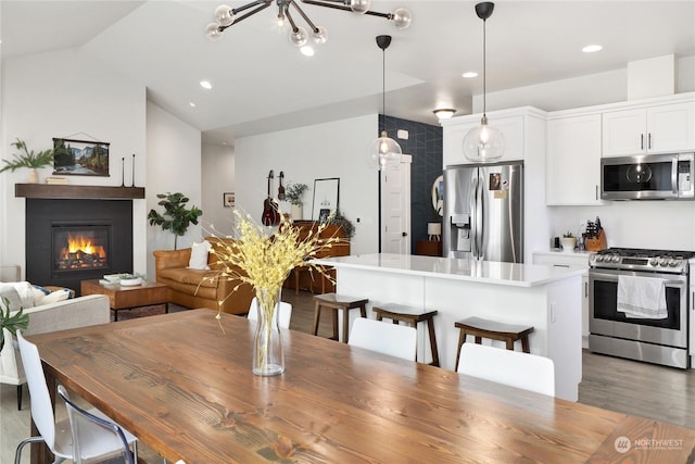 dining area with wood-type flooring and vaulted ceiling