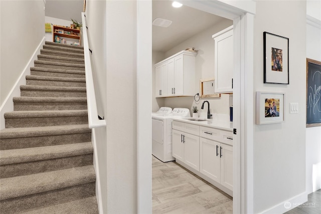 clothes washing area featuring light hardwood / wood-style floors, cabinets, separate washer and dryer, and sink