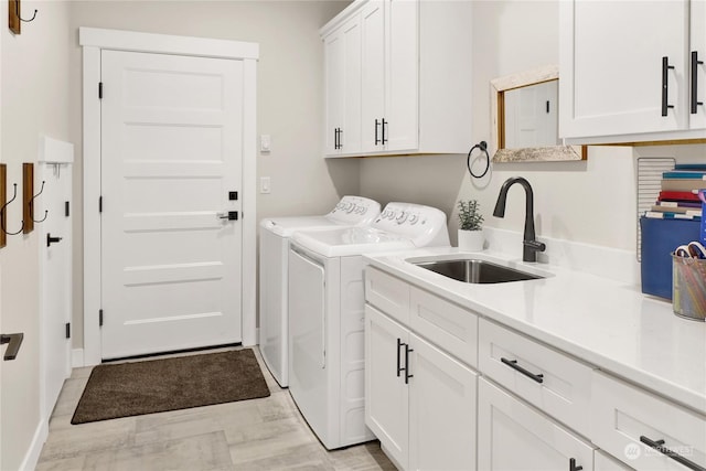 clothes washing area with independent washer and dryer, cabinets, and sink