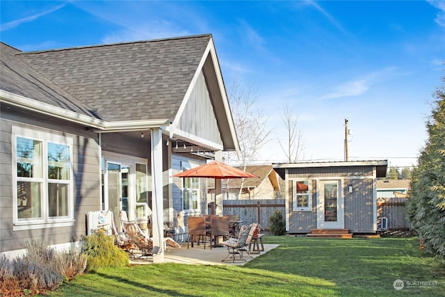 back of house featuring an outbuilding, a patio, and a lawn