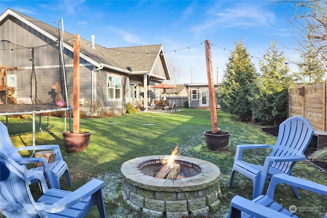 view of yard with a trampoline and a fire pit