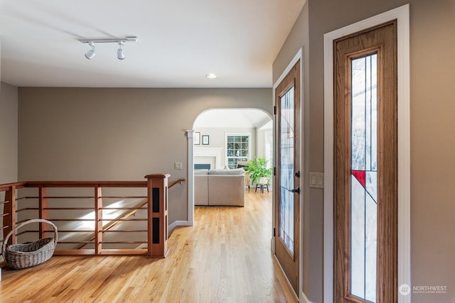 entryway featuring arched walkways, a fireplace, recessed lighting, track lighting, and wood finished floors