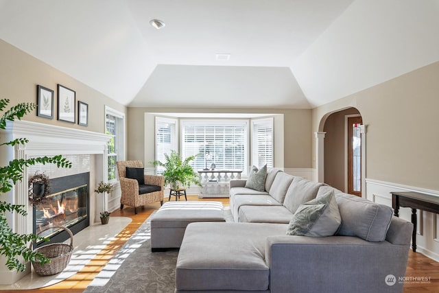 living room featuring lofted ceiling, a tile fireplace, a wealth of natural light, and arched walkways