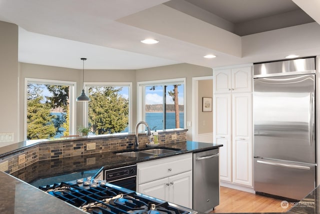 kitchen with decorative backsplash, appliances with stainless steel finishes, light wood-type flooring, white cabinetry, and a sink