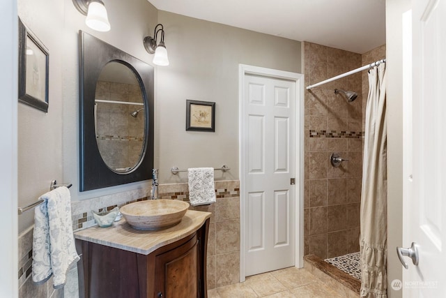 full bathroom featuring tile patterned flooring, a wainscoted wall, vanity, tile walls, and a tile shower