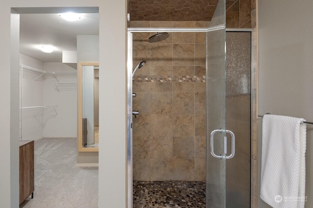 bathroom featuring a stall shower, a spacious closet, and baseboards