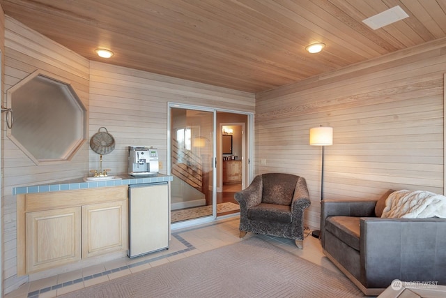 sitting room with recessed lighting, wooden ceiling, light tile patterned flooring, and wooden walls