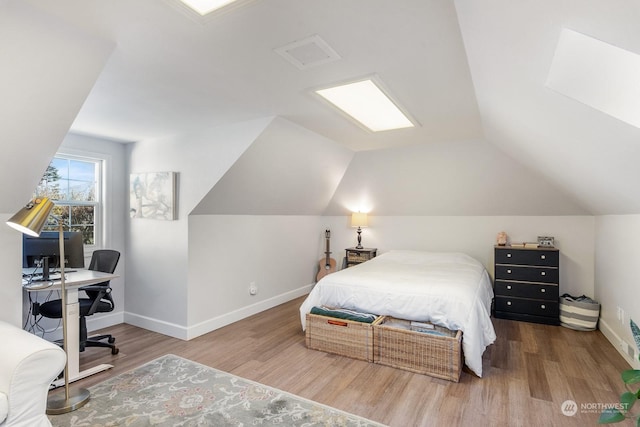 bedroom featuring lofted ceiling, visible vents, baseboards, and wood finished floors