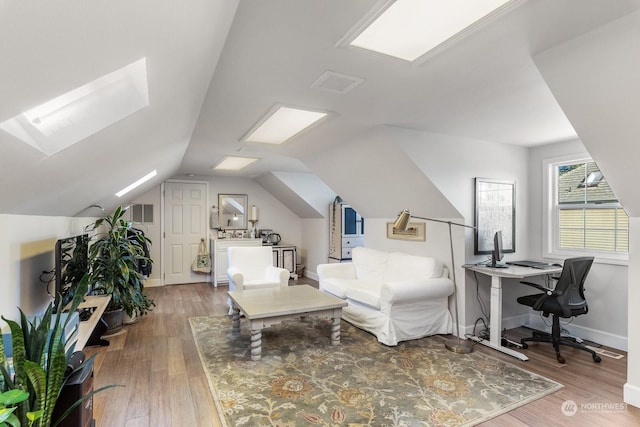 bedroom featuring vaulted ceiling with skylight, wood finished floors, visible vents, and baseboards