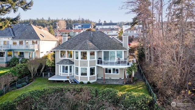 back of house with a yard, a chimney, a sunroom, fence, and a residential view