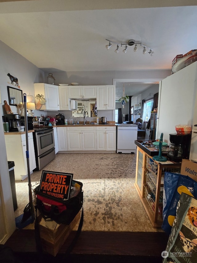 kitchen with fridge, white cabinets, sink, and electric range