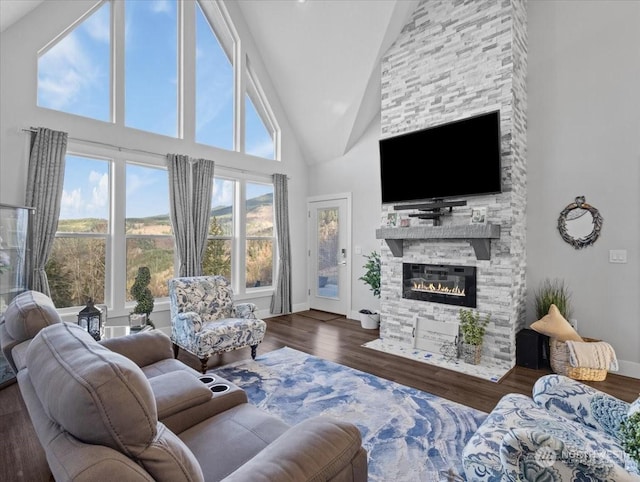 living room with dark hardwood / wood-style flooring, a stone fireplace, and high vaulted ceiling