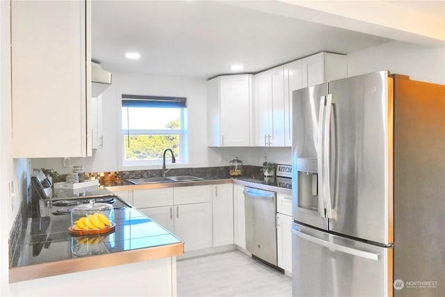 kitchen featuring stainless steel appliances, sink, white cabinets, and light hardwood / wood-style floors