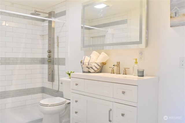 bathroom with a tile shower, vanity, and toilet