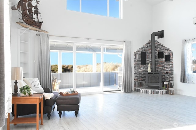 living room with hardwood / wood-style flooring, a towering ceiling, and a wood stove