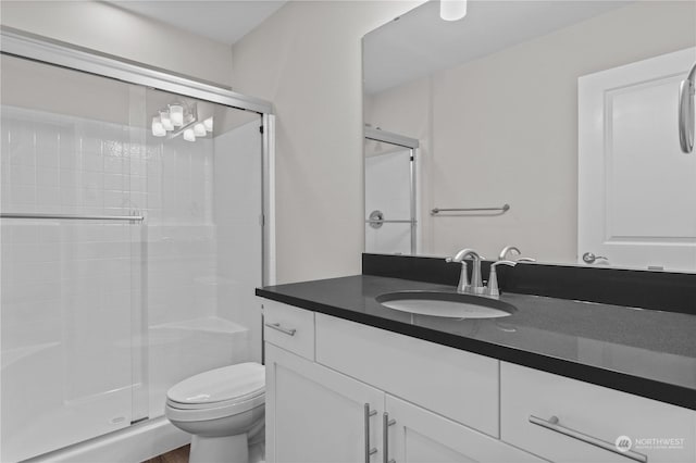 bathroom with vanity, toilet, and a shower with shower door