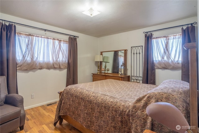 bedroom with visible vents, light wood-style flooring, and baseboards