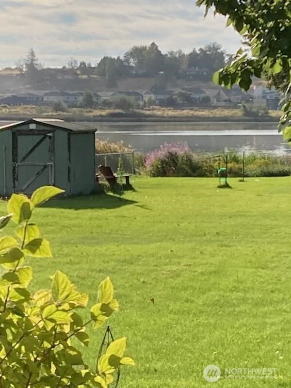 view of yard with an outbuilding, a shed, and a water view