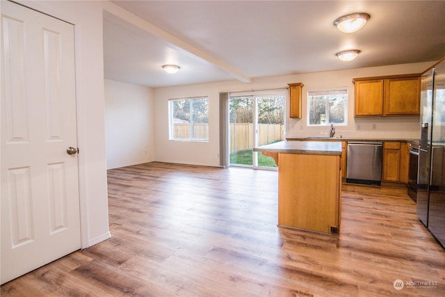 kitchen featuring sink, a center island, stainless steel dishwasher, beam ceiling, and light hardwood / wood-style flooring