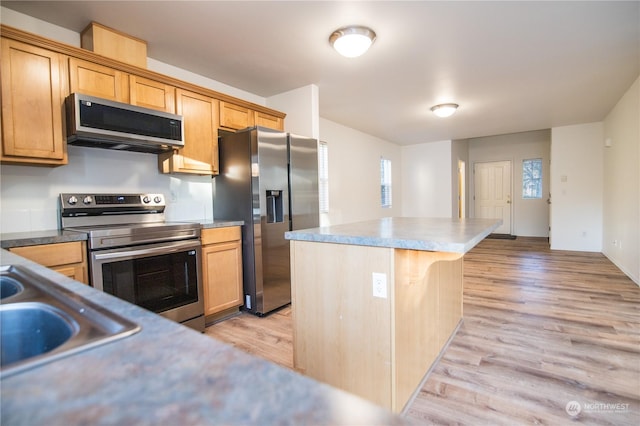 kitchen with a kitchen breakfast bar, appliances with stainless steel finishes, a center island, and light wood-type flooring