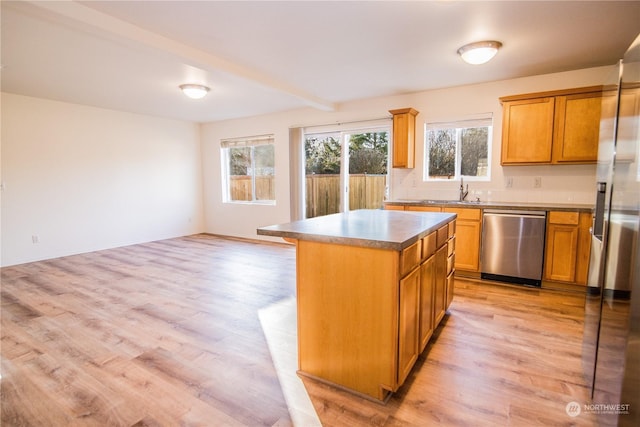 kitchen with stainless steel appliances, a center island, light hardwood / wood-style floors, and beam ceiling