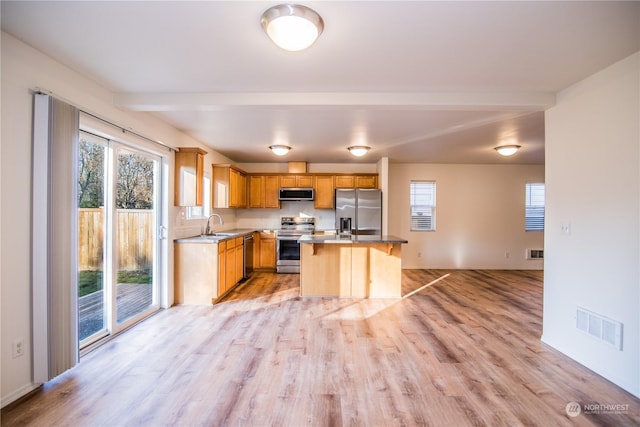 kitchen featuring stainless steel appliances, a kitchen island, and a healthy amount of sunlight