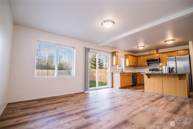 kitchen featuring sink, light hardwood / wood-style flooring, a kitchen breakfast bar, beamed ceiling, and stainless steel appliances