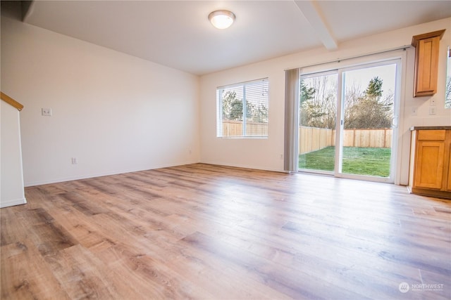 unfurnished living room featuring light hardwood / wood-style flooring and beamed ceiling