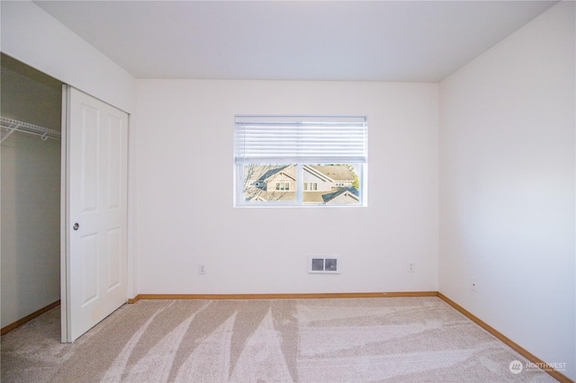 unfurnished bedroom featuring light colored carpet and a closet