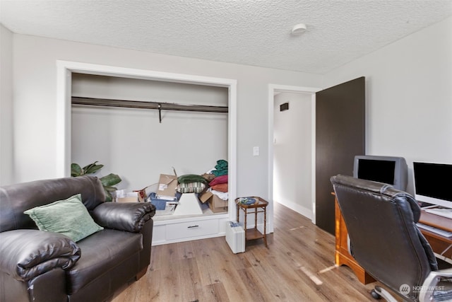 home office with a textured ceiling and light hardwood / wood-style floors