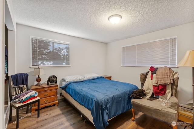 bedroom with hardwood / wood-style floors and a textured ceiling