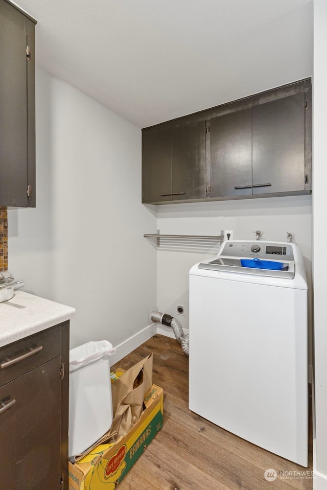 clothes washing area with washer / clothes dryer, cabinets, and light wood-type flooring