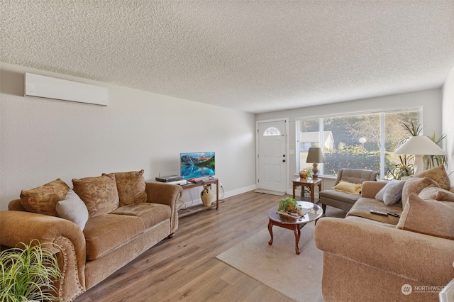 living room featuring a wall mounted air conditioner, hardwood / wood-style flooring, and a textured ceiling