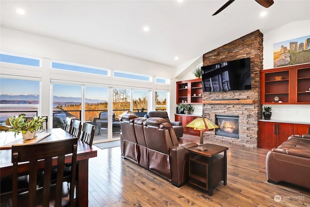 living room with hardwood / wood-style flooring, ceiling fan, a fireplace, and high vaulted ceiling