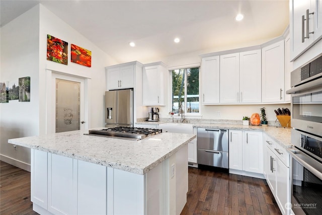 kitchen with sink, appliances with stainless steel finishes, light stone counters, white cabinets, and a kitchen island