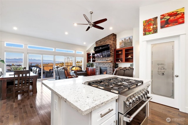 kitchen featuring stainless steel stove, a fireplace, white cabinetry, lofted ceiling, and dark wood-type flooring