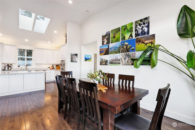 dining room with dark hardwood / wood-style flooring and vaulted ceiling with skylight