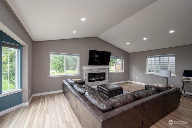 living room featuring lofted ceiling, a fireplace, and light hardwood / wood-style flooring