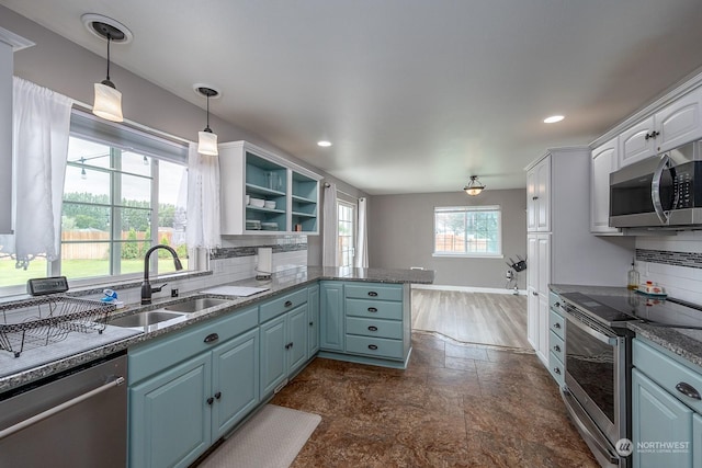 kitchen with sink, white cabinetry, backsplash, stainless steel appliances, and kitchen peninsula