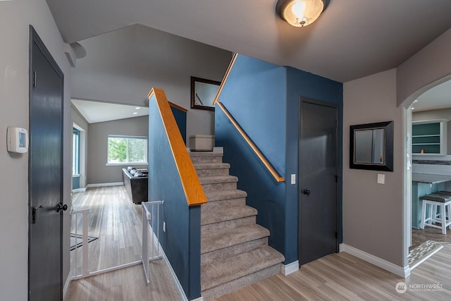 staircase featuring hardwood / wood-style flooring and lofted ceiling