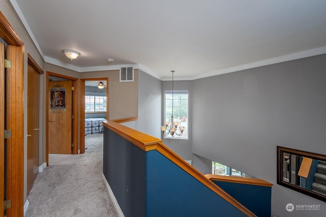 corridor featuring ornamental molding, plenty of natural light, light carpet, and a notable chandelier